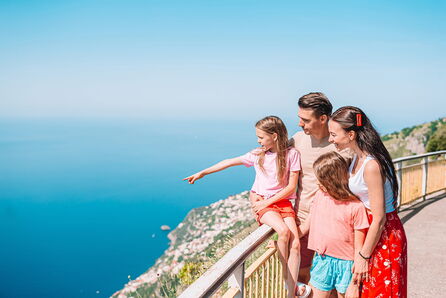 Familie mit zwei Kindern auf einer Aussichtsplattform mit Panoramablick auf die Küste und das Meer.